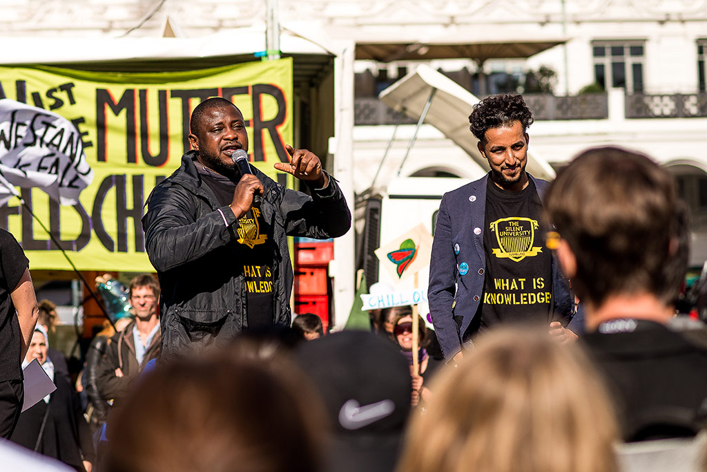 Beginn der We’ll Come United-Parade, Abimbola Ayodele am Mikrofon © Daniel Nide